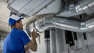 Foto, Lüftungstechniker arbeitet an einer an der Decke montierten Lüftungsanlage.
