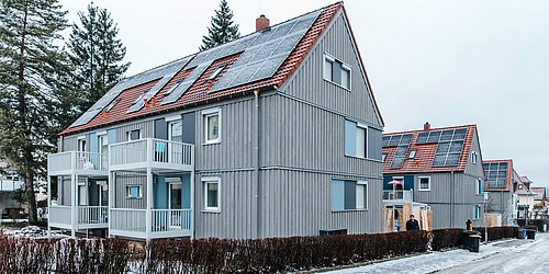 Foto, Siedlung mehrere Mehrfamilienhäuser mit Photovoltaikanlagen auf den Dächern. 