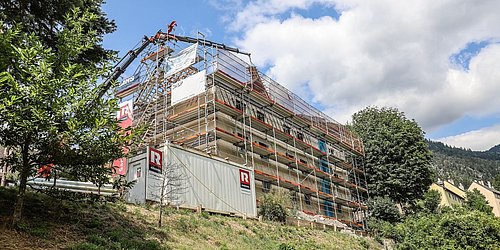 Foto, Mehrstöckiges Gebäude in ländlicher Umgebung mit Gerüst und Bauplanen, Bauarbeiten im Gange