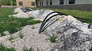 Foto, aufgewühltes Erdreich aus dem Kunststoffrohre einer Geothermieanlage herausragen.