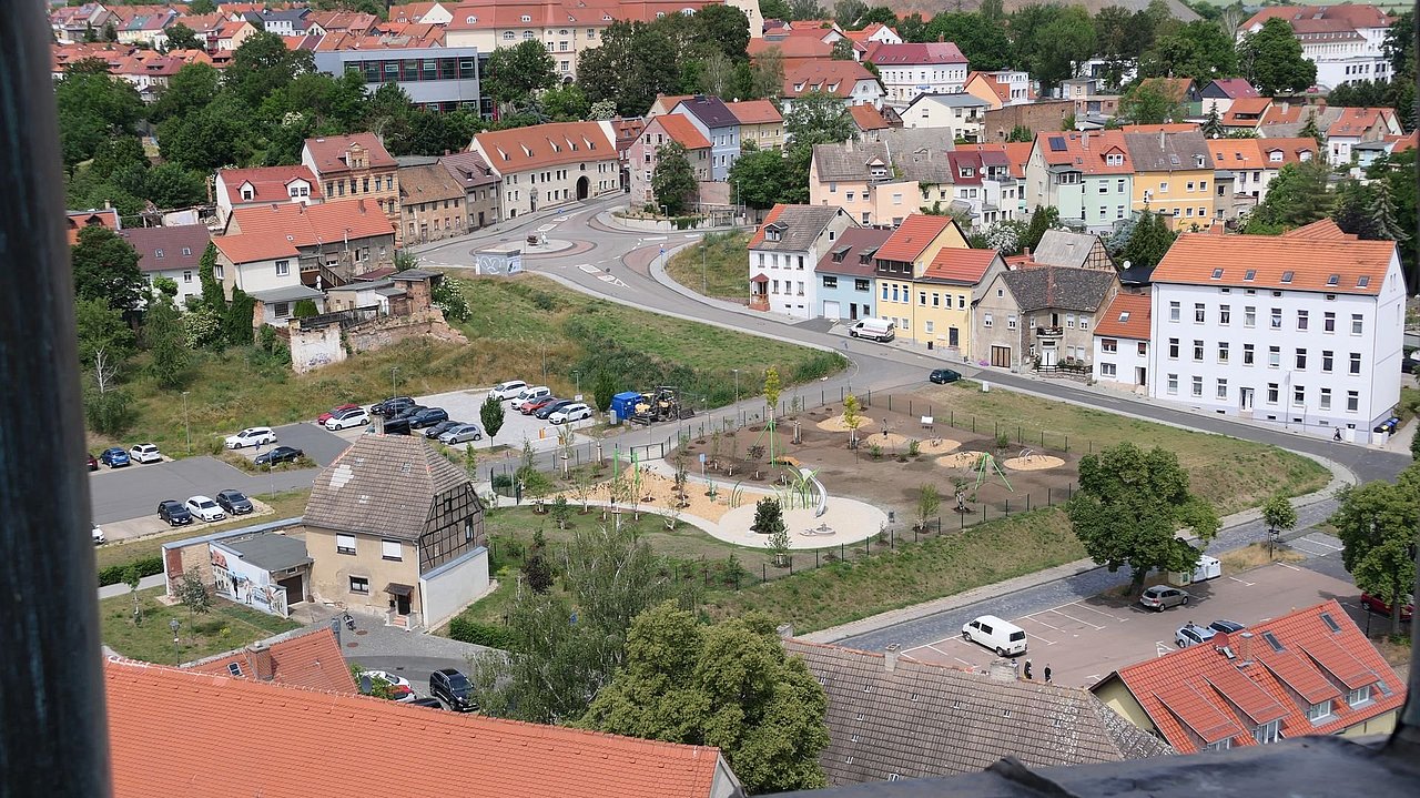 Foto, Blick auf ein Wohnviertel mit bunten Häusern, einem Spielplatz und Parkplätzen in einer Kleinstadt