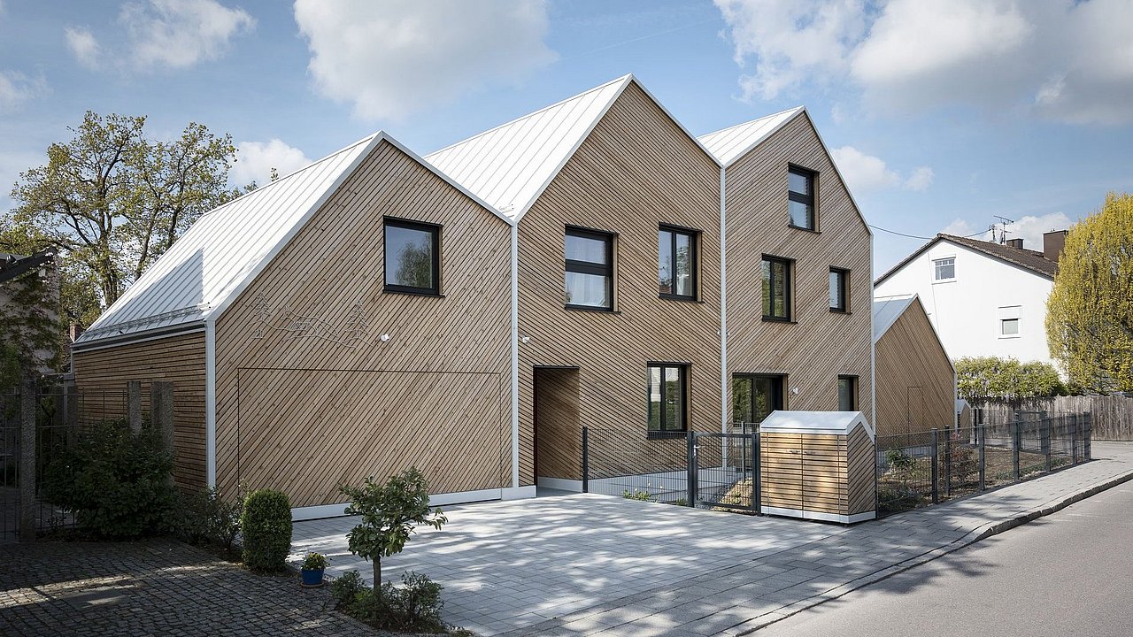 Foto, Modernes Wohnhaus mit Holzfassade und drei Giebeln, große Fenster, Einfahrt und kleiner Garten an einer ruhigen Straße