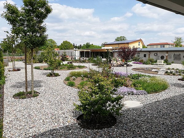 Foto, Außenanlage mit grobem Rundkies und verschiedenen bepflanzen Beeten
