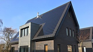 Foto, Neubau eines Einfamilienhauses, das Dach ist mit modernen Solarziegeln gedeckt.