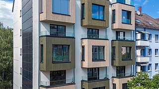 Foto, Außenansicht eines modern sanierte Mehrfamilienhauses mit Erkern, die mit Holz verkleidet sind