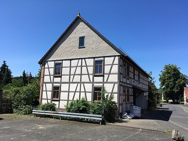 Foto, Fachwerkhaus mit weißer Fassade und braunen Holzbalken an einer ruhigen Straße