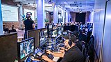 Foto, Techniker steuern Videoproduktion mit mehreren Monitoren bei einer Konferenzveranstaltung in einem großen Raum mit Publikum