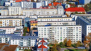 Foto, Blick von oben auf eine urbanes Gebiet mit mehreren sanierten Plattenbauten.