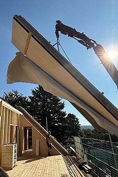 Foto, Blauer Himmel mit Haus, Dachstuhl im Ausbau, ein Fassadenelement wird mit dem Krank angeliefert