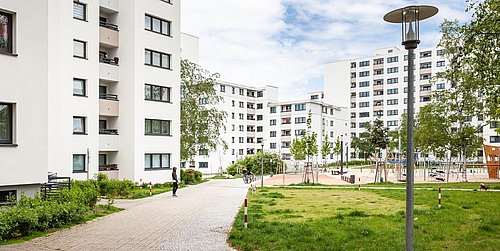 Foto, Innenhof einer modernen Wohnsiedlung aus Mehrfamilienhäusern mit Grünflächen und großem Spielplatz.