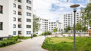 Foto, Innenhof einer modernen Wohnsiedlung aus Mehrfamilienhäusern mit Grünflächen und großem Spielplatz.