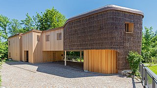 Foto, das Rosana Waldhaus mit einer mit Holz und Weidenzweigen verkleideten Fassade in organischer Form.