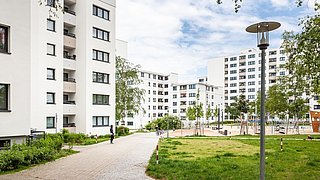 Foto, Innenhof einer modernen Wohnsiedlung aus Mehrfamilienhäusern mit Grünflächen und großem Spielplatz.