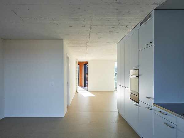 Foto, Moderner offener Wohnraum mit weißer Küchenzeile, eingebautem Backofen und großem Fenster am Ende des Raums