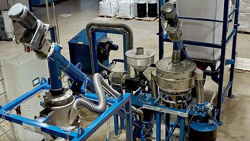 Foto, Industrielle Anlage mit blauer Metallrahmenkonstruktion, mehreren Motoren, Rohren und Trichtern in einer Halle.