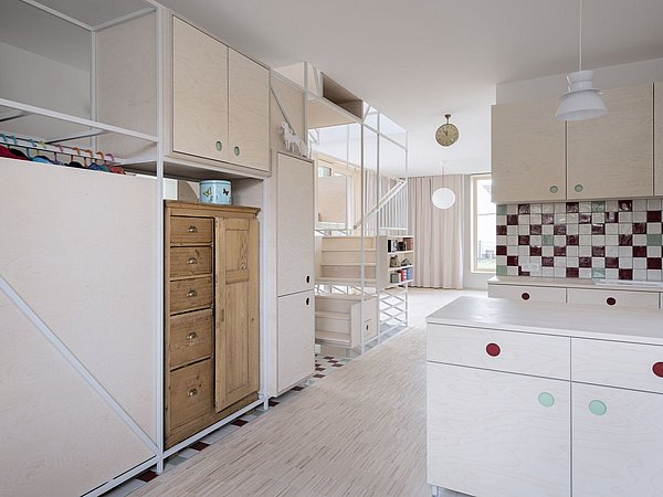 Foto, Offene, helle Wohnung mit weißen Regalen, Holzkommode und Küchenzeile mit bunten Griffen