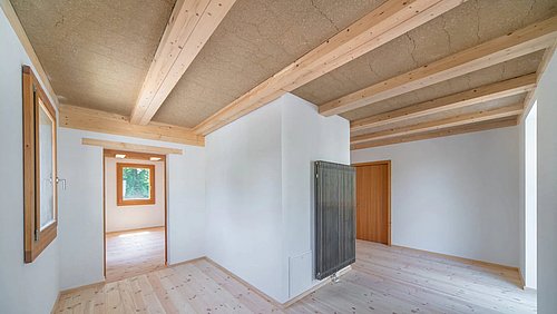 Foto, leerer Raum mit hellen Wänden, Holzfußboden und sichtbaren Holzbalken an der Decke.