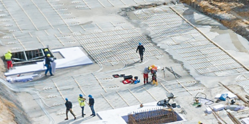 Foto, Baustelle mit mehreren Arbeitern, die Erdwärmekollektoren auf einer Betonfläche installieren