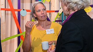Foto, zwei Frauen im Gespräch auf einer Veranstaltung.