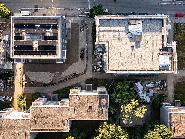Luftaufnahme eines Quartiers mit mehreren Gebäuden, links auf dem Dach eine Photovoltaikanlage sichtbar