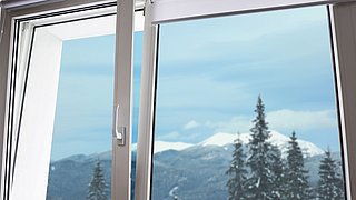 Foto, Blick aus einem geöffneten Fenster auf schneebedeckte Tannen und Berge im Hintergrund.