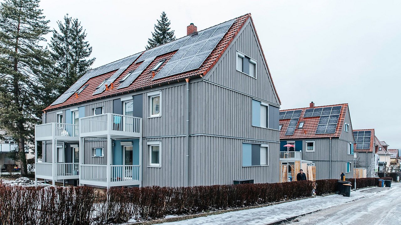 Foto, Siedlung mehrere Mehrfamilienhäuser mit Photovoltaikanlagen auf den Dächern.