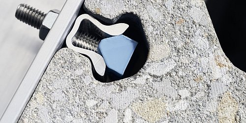 Foto, Nahaufnahme einer Metallhalterung mit Schraube in einem Betonmauerstein.