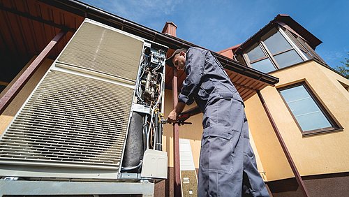 Foto, ein Techniker arbeitet an einer Wärmepumpe.