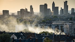 Foto, Rauch aus Schornsteinen über den Dächern einer Stadt.