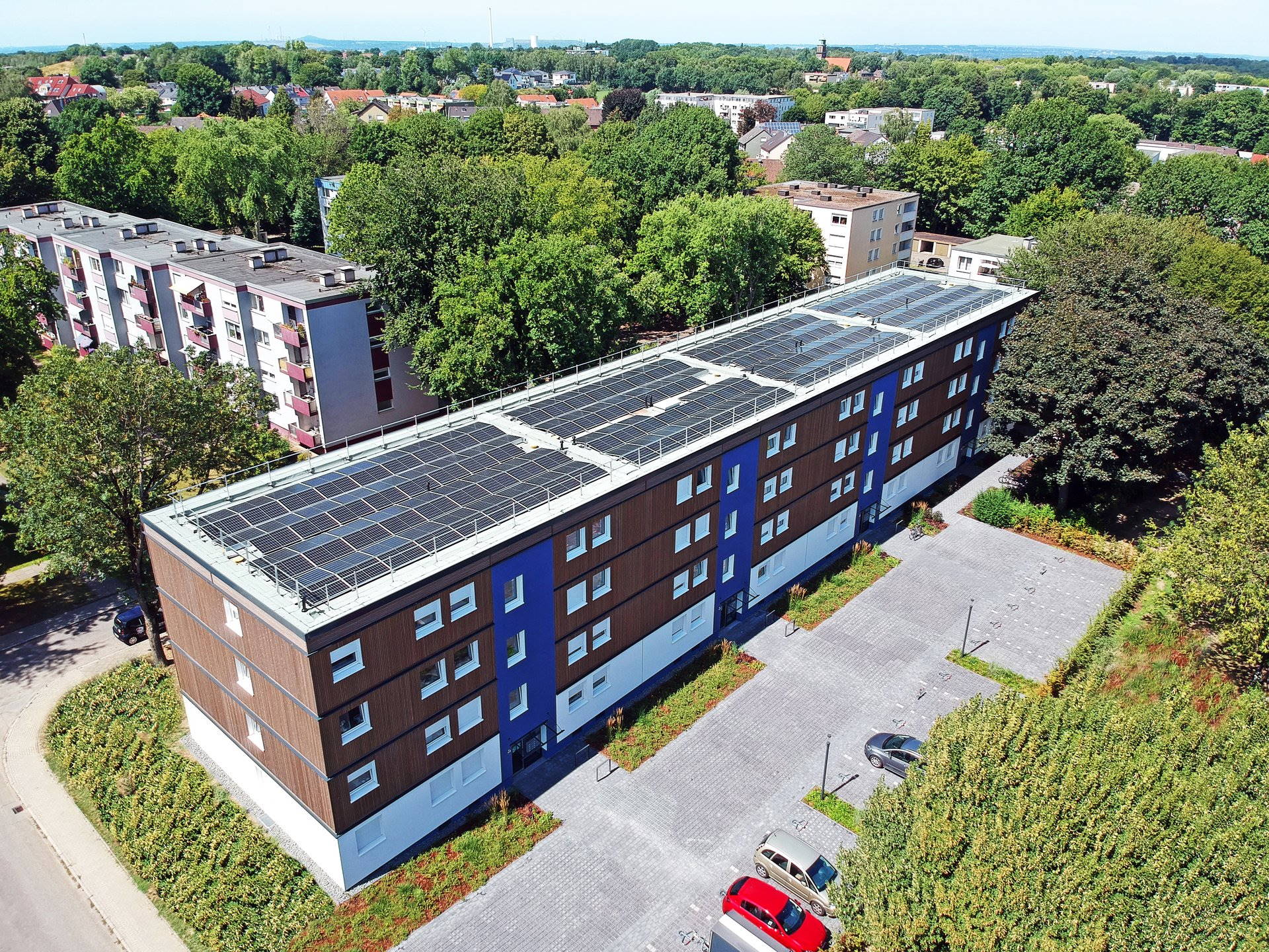 Foto, Vogelperspektive auf Mehrfamilienhaus mit Photovoltaik-Kollektoren auf dem Dach.