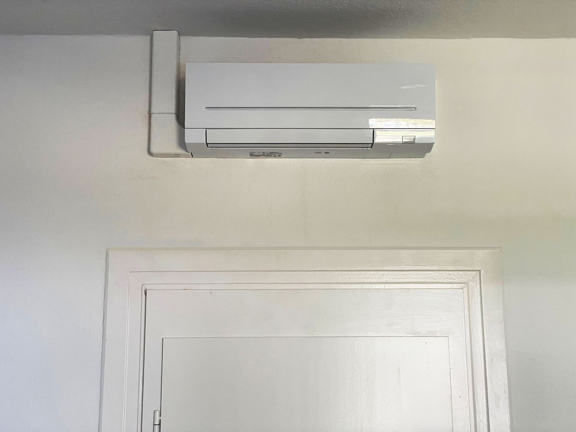 Foto, Inneneinheit einer Luft-Luft-Wärmepumpe über einer weißen Tür in einem Innenraum