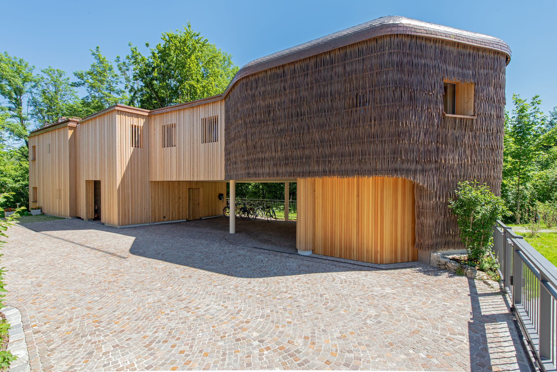 Foto, das Rosana Waldhaus mit einer mit Holz und Weidenzweigen verkleideten Fassade in organischer Form.