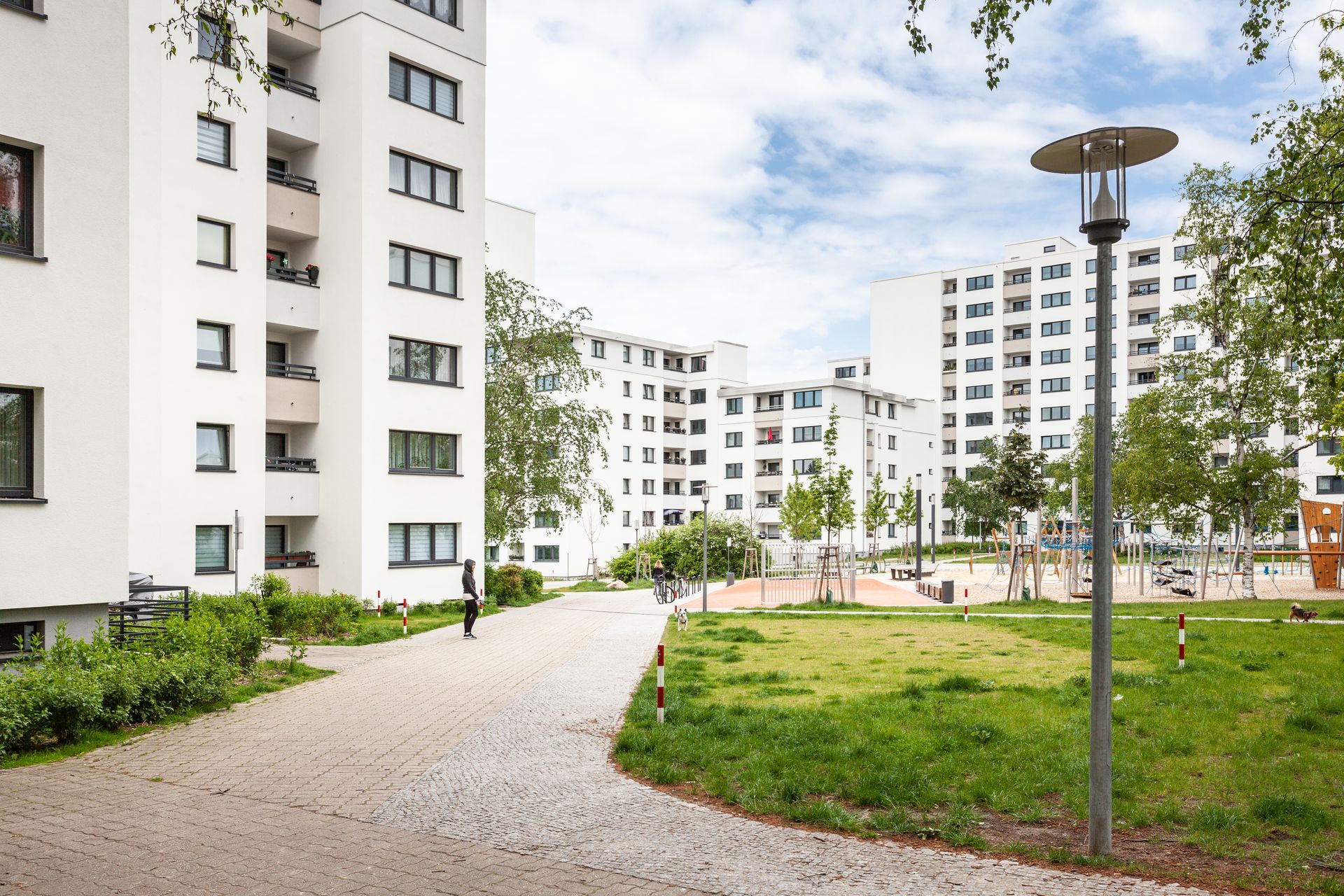 Foto, Innenhof einer modernen Wohnsiedlung aus Mehrfamilienhäusern mit Grünflächen und großem Spielplatz.