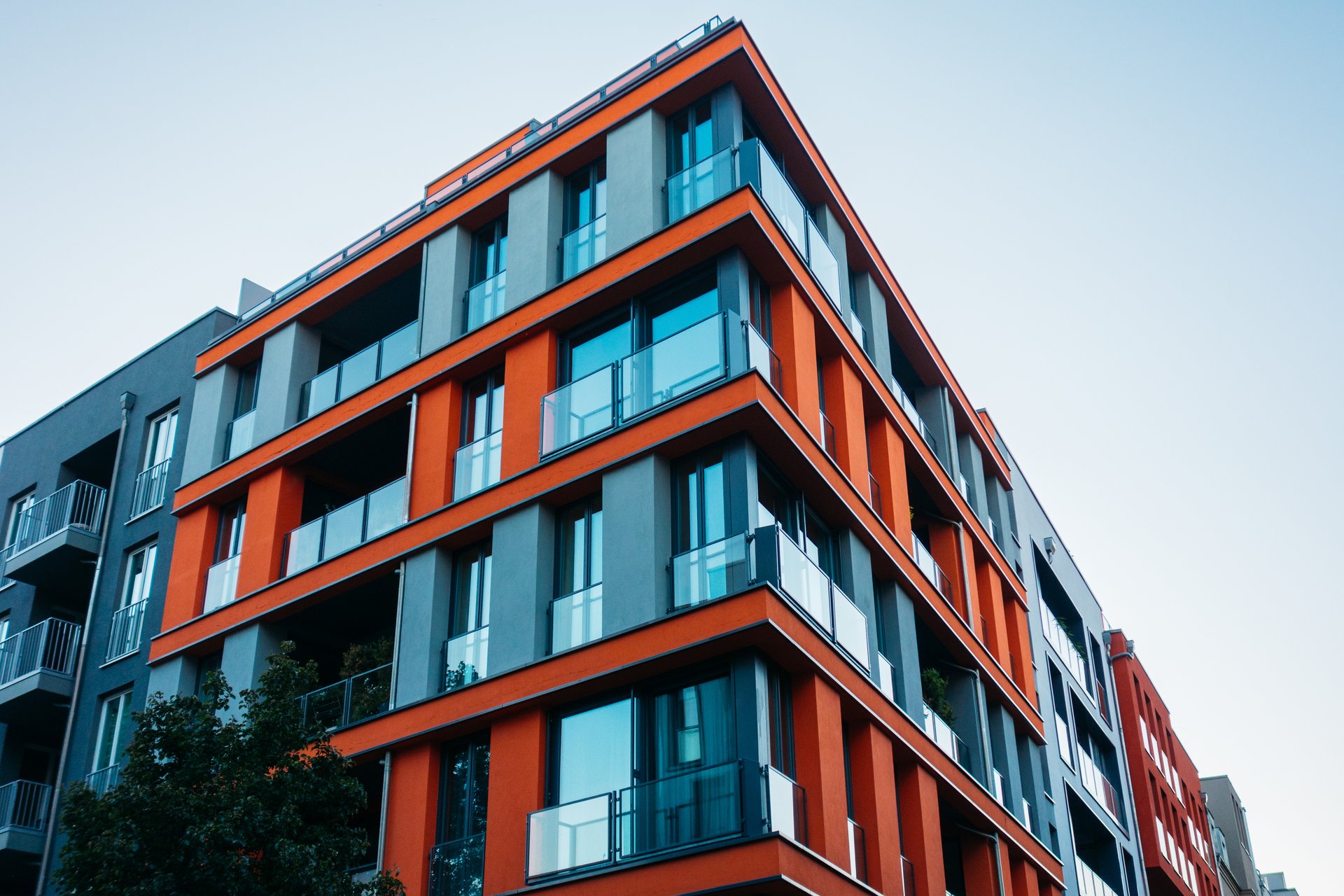 Foto, Blick hinauf an der Fassade eines mehrstöckigen Neubaus mit auffälligen roten Fassadenelementen.
