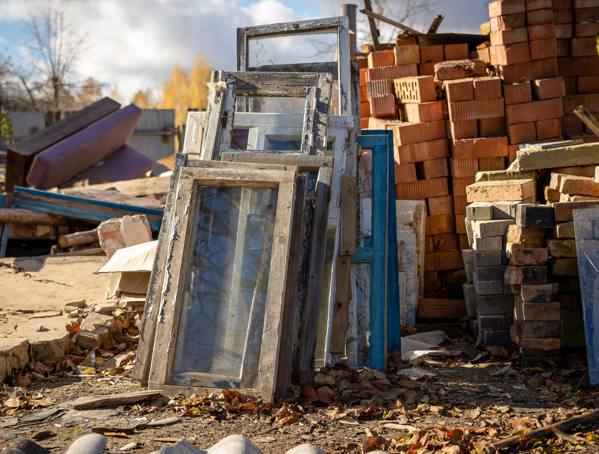 Foto, im Vordergund ein großer Stapel alter Ziegelsteine, daran angelehnt mehere alte Fensterelemente. Im Hintergrund weitere Bauabfälle.