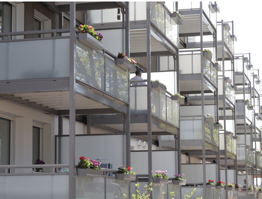 Foto, Balkone mit bepflanzten Blumenkästen an einem Mehrfamilienhaus.